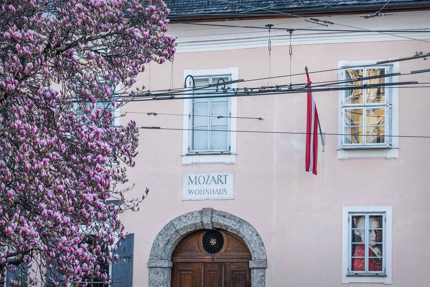 Mozart Wohnhaus entrance on Makartplatz framed by spring magnolia blossoms in Salzburg.
