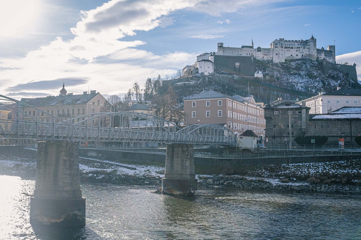 Mozartsteg footbridge with Hohensalzburg Fortress rising above the Salzach in winter in Salzburg.