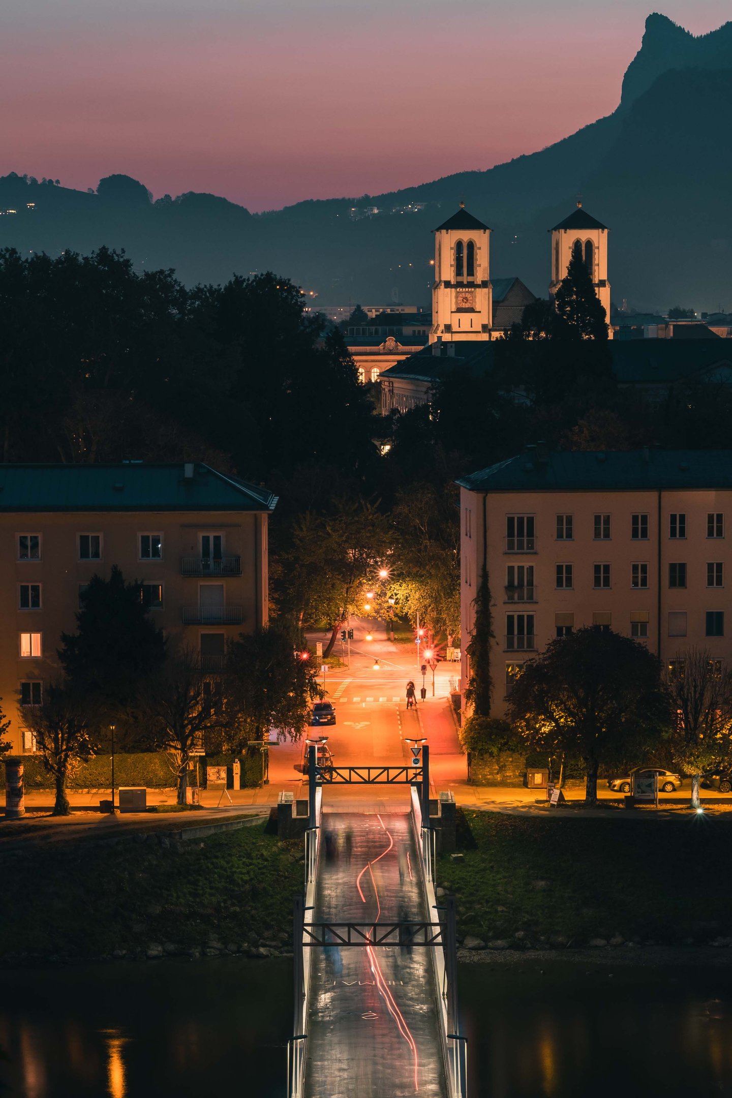 Footbridge Müllnersteg leading toward Mülln church at dusk in Salzburg.