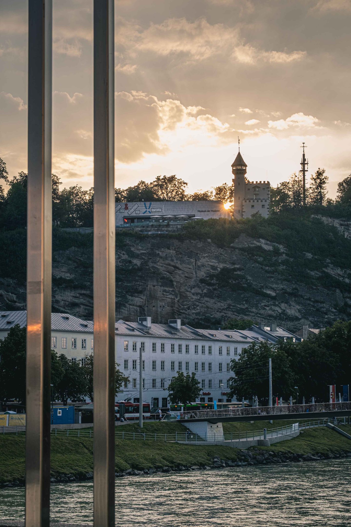 Museum der Moderne and Stadtalm tower on Monchsberg cliff at sunset seen across the Salzach in Salzburg