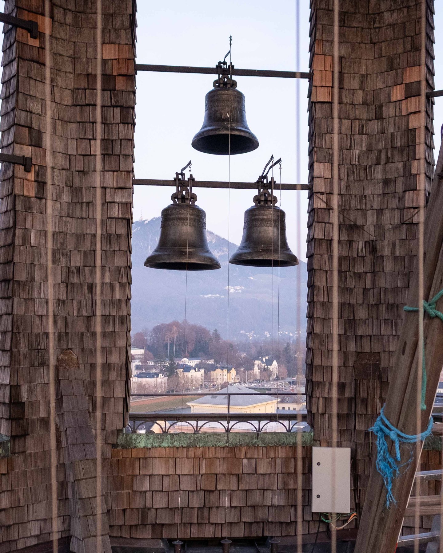 Carillon bells of the Glockenspiel with Nonnberg Abbey and mountains visible through frame in Salzburg