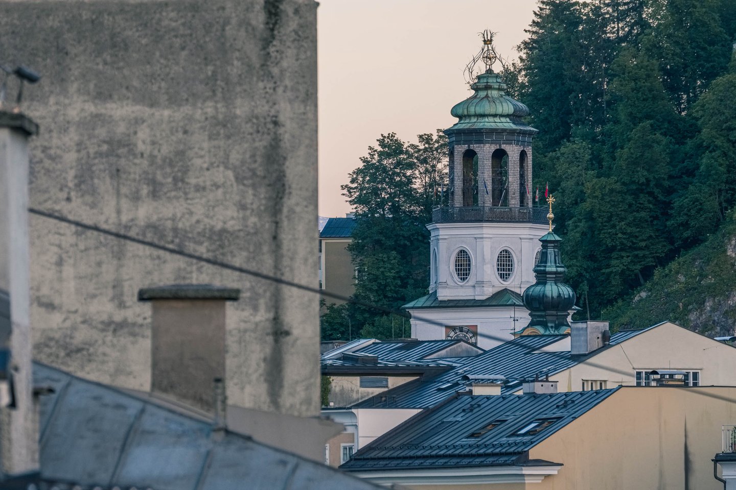Glockenspiel tower of the Neue Residenz with arched belfry lantern rising above Salzburg Altstadt rooftops at dusk
