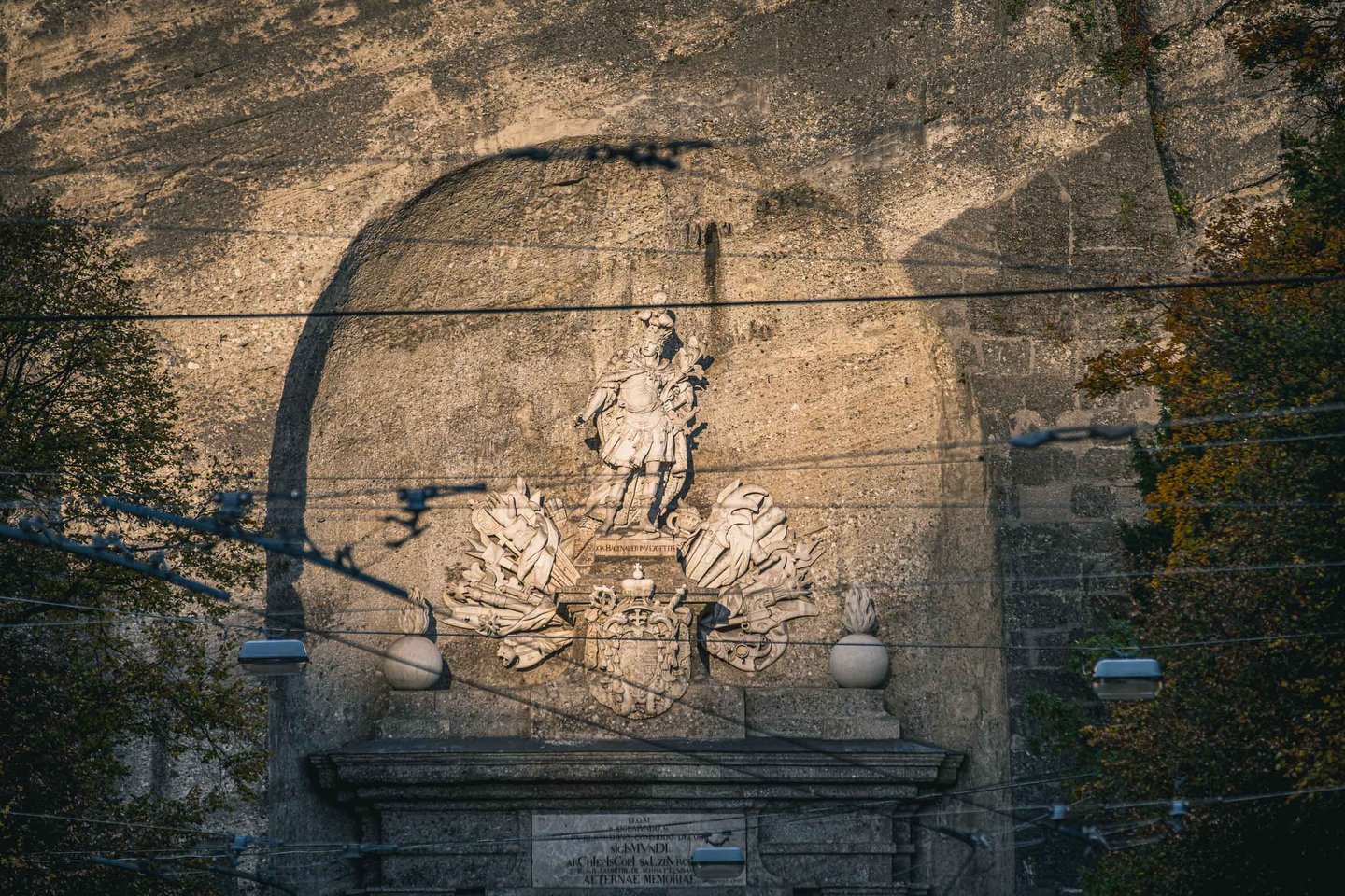 Prince-archbishop statue and coat of arms above the Neutor tunnel portal on Monchsberg in Salzburg.