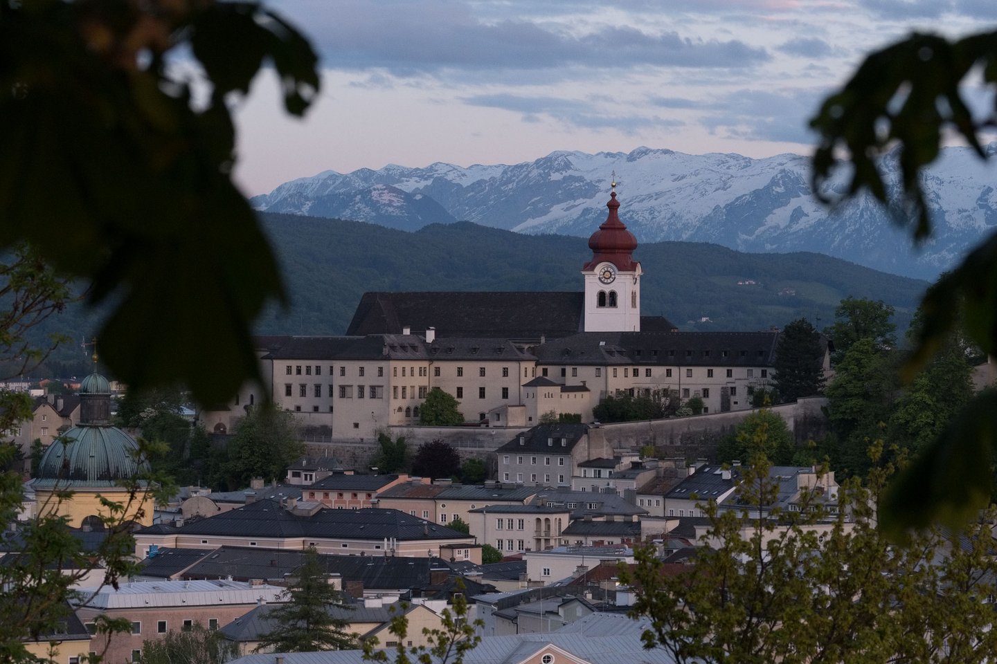 Nonnberg Abbey red onion domed tower with snowy Alps behind in Salzburg.