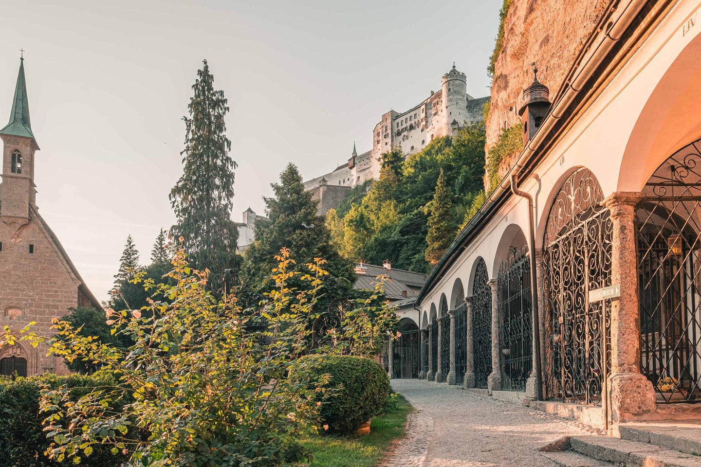 Arcade crypts of St Peter cemetery with Hohensalzburg Fortress rising on the cliff above in Salzburg.
