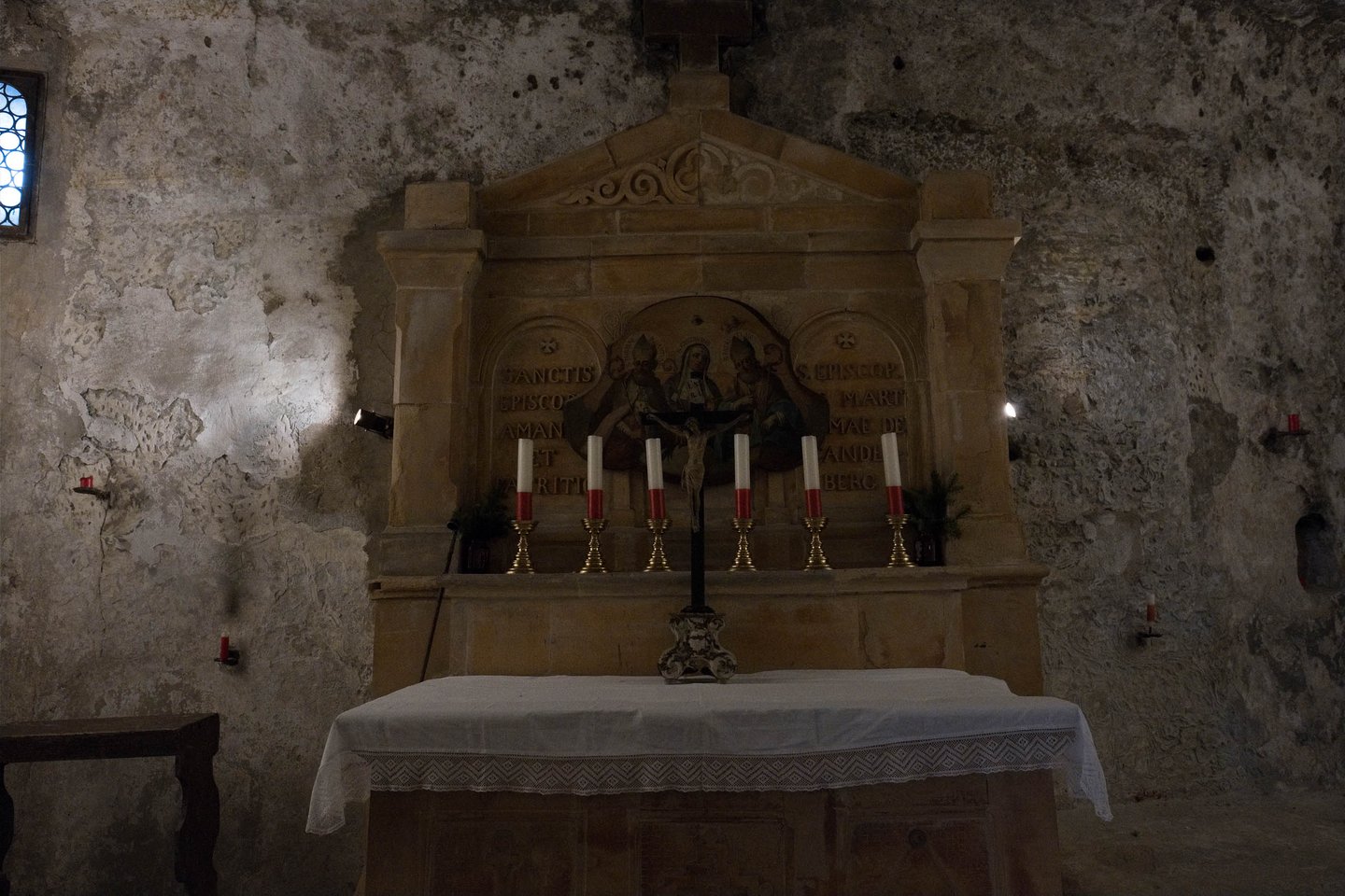 Altar carved into the rock wall with candles inside the catacombs chapel at Petersfriedhof in Salzburg.