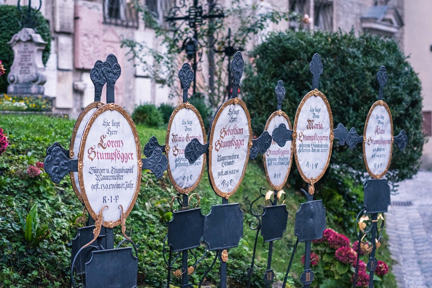 Wrought iron grave markers with painted oval plaques at St Peter cemetery in Salzburg old town