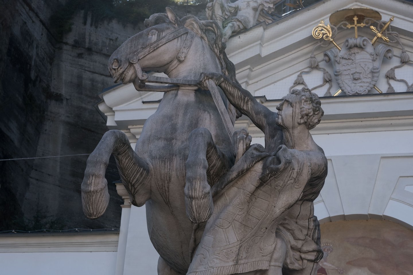Pferdeschwemme rearing horse and tamer statue with coat of arms above in Salzburg