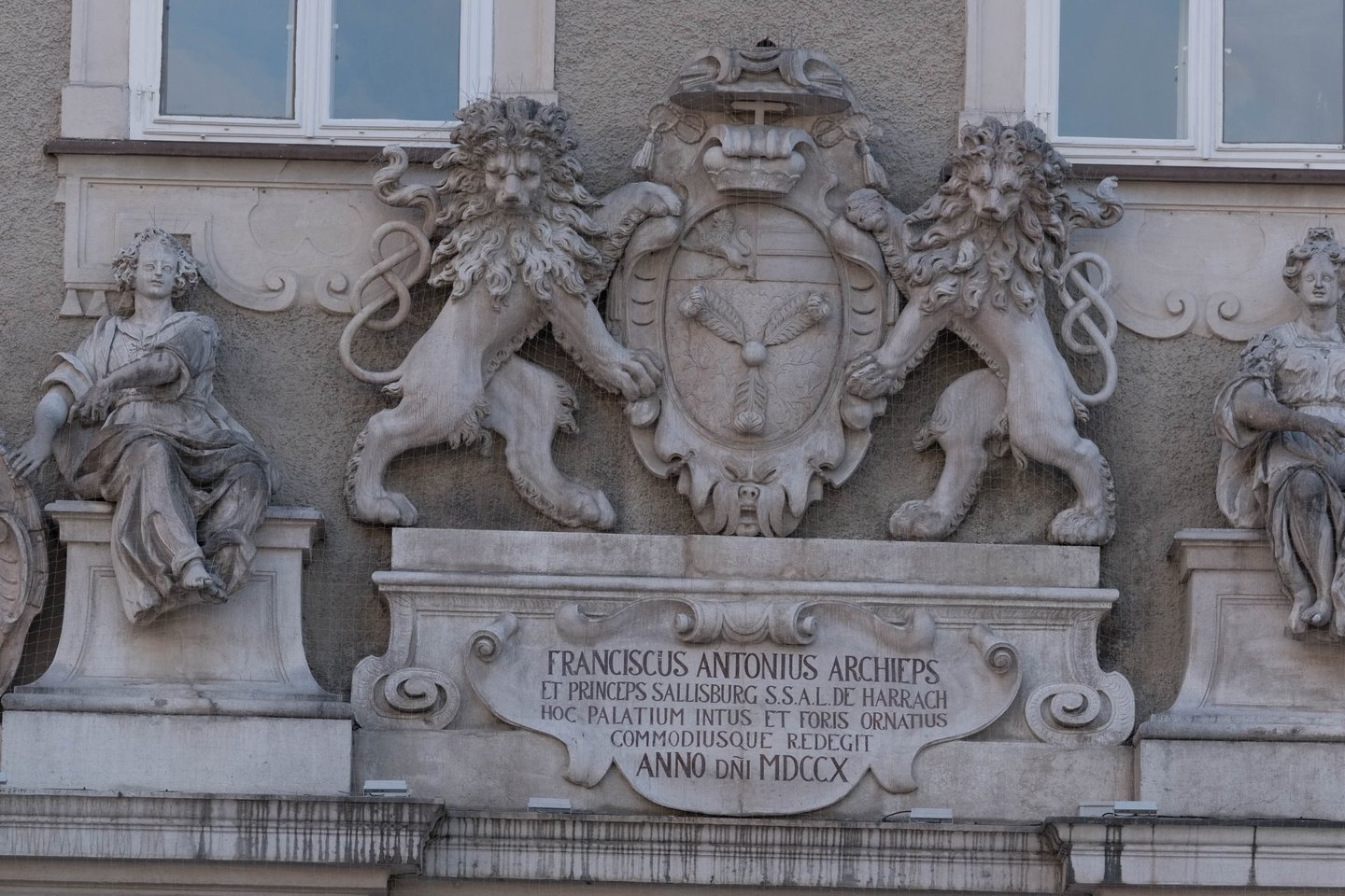 Stone coat of arms of Archbishop Franz Anton Harrach with two flanking lions and cherubs and Latin inscription dated MDCCX 1710 on the Residenz facade