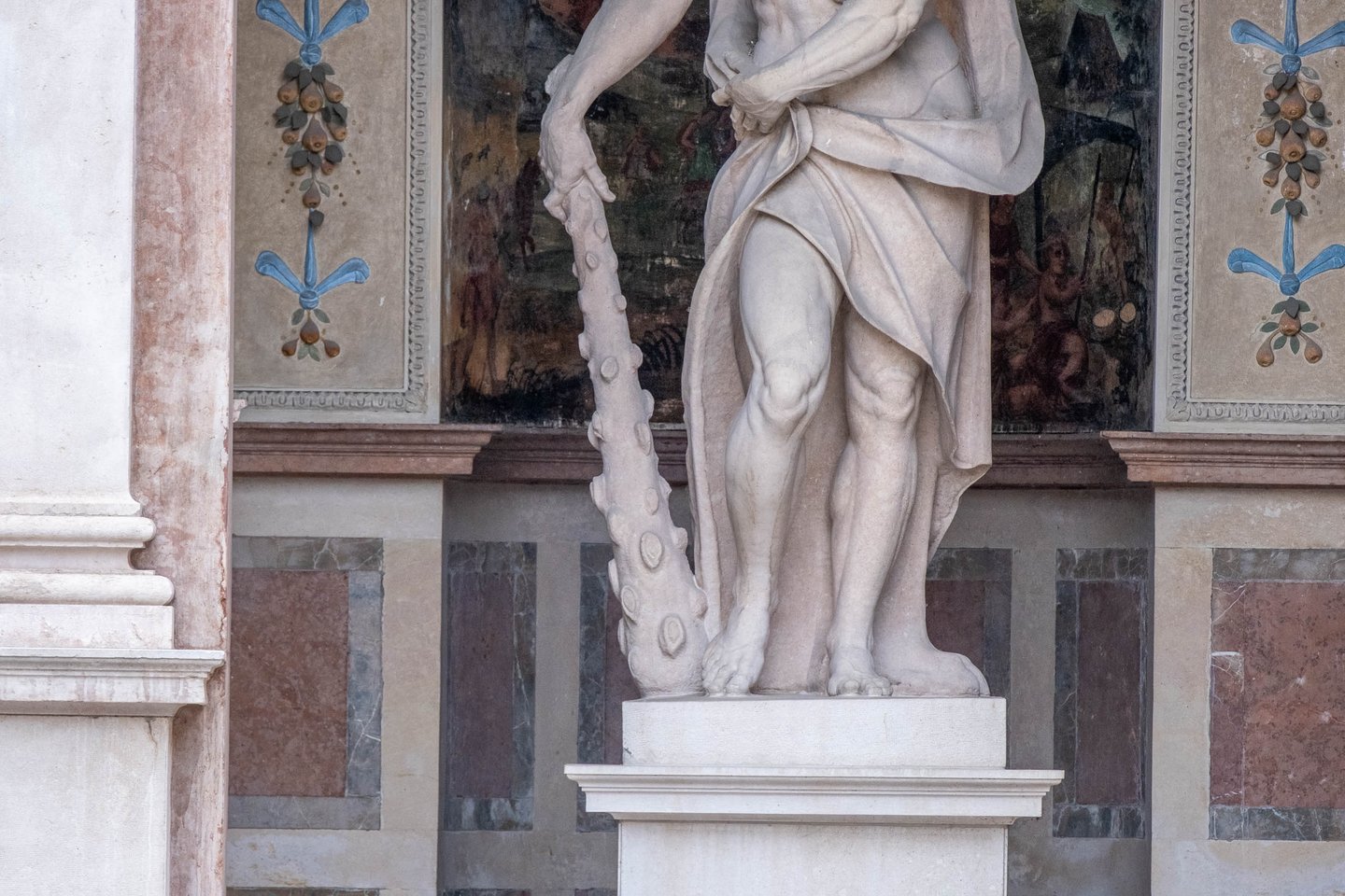 Marble Hercules statue with club against a frescoed wall inside the Salzburg Residenz in Salzburg old town