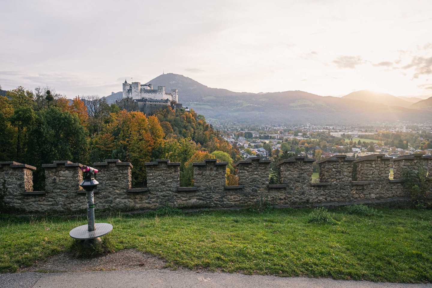 Sunrise view of Hohensalzburg Fortress from Richterhoehe stone wall viewpoint in Salzburg.