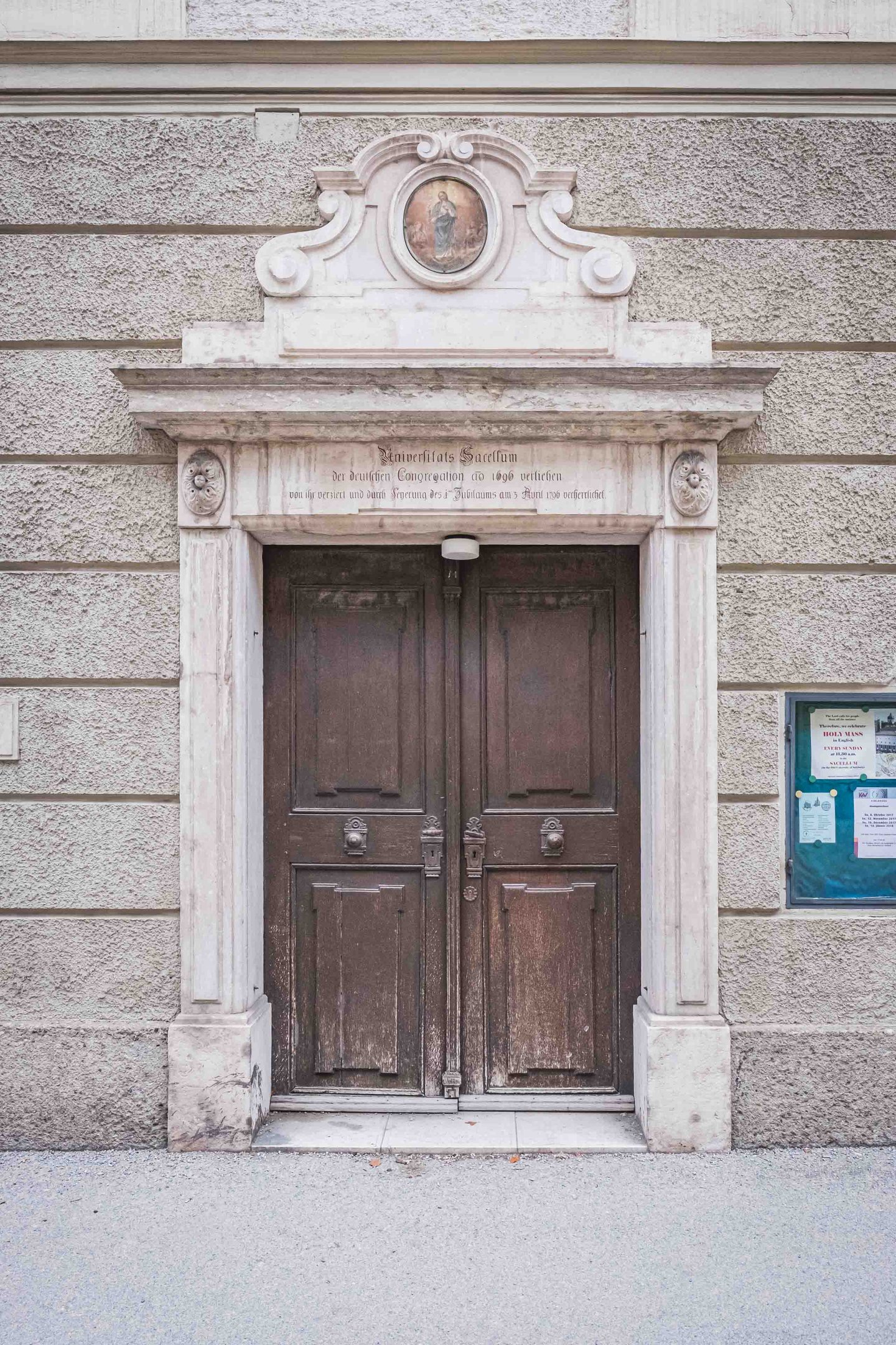 Wooden double door with Latin inscription marks the entrance to the Sacellum chapel in Salzburg