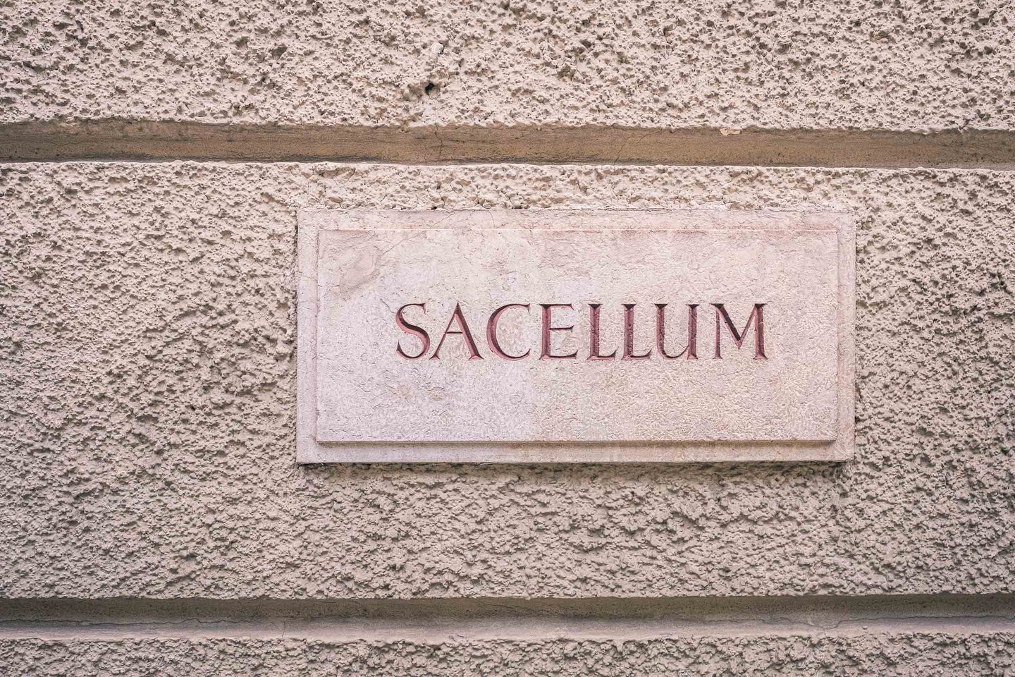 Stone nameplate reading SACELLUM marks the university chapel facade in Salzburg old town