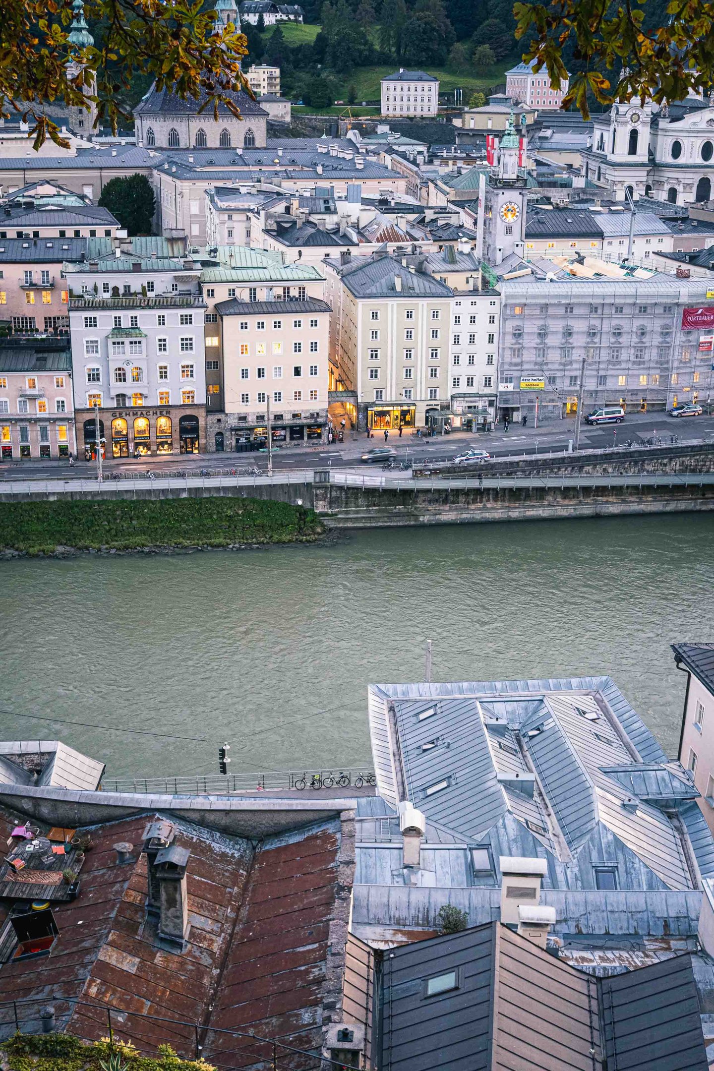 Salzach river flowing past Altstadt facades with Steingasse rooftops in foreground at dusk in Salzburg