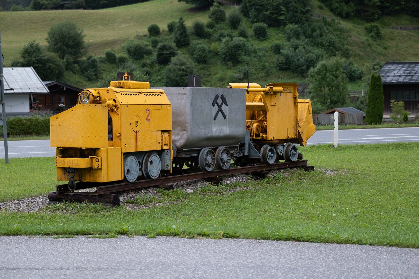 Yellow mining locomotive with ore wagon displayed on rails outside the Salzbergwerk in Berchtesgaden