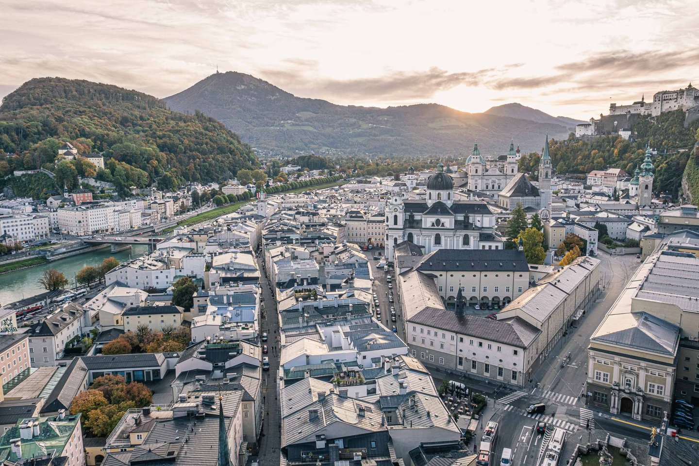 Aerial view of Salzburg old town at sunrise with Kollegienkirche dome and Hohensalzburg Fortress on the right.