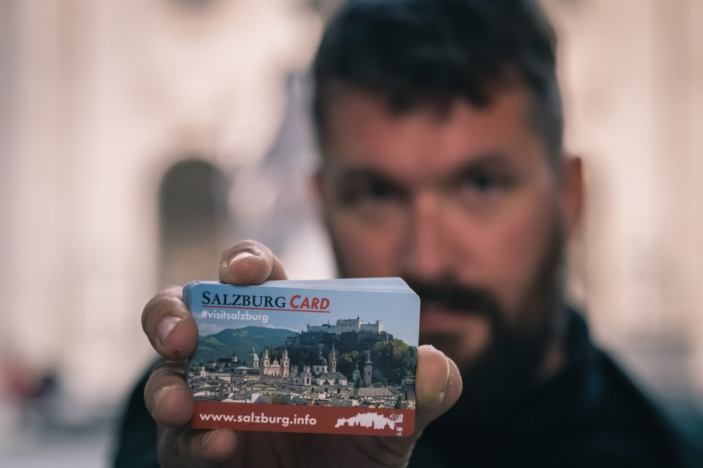 Close-up of Salzburg Card held toward camera with fortress panorama graphic in Salzburg