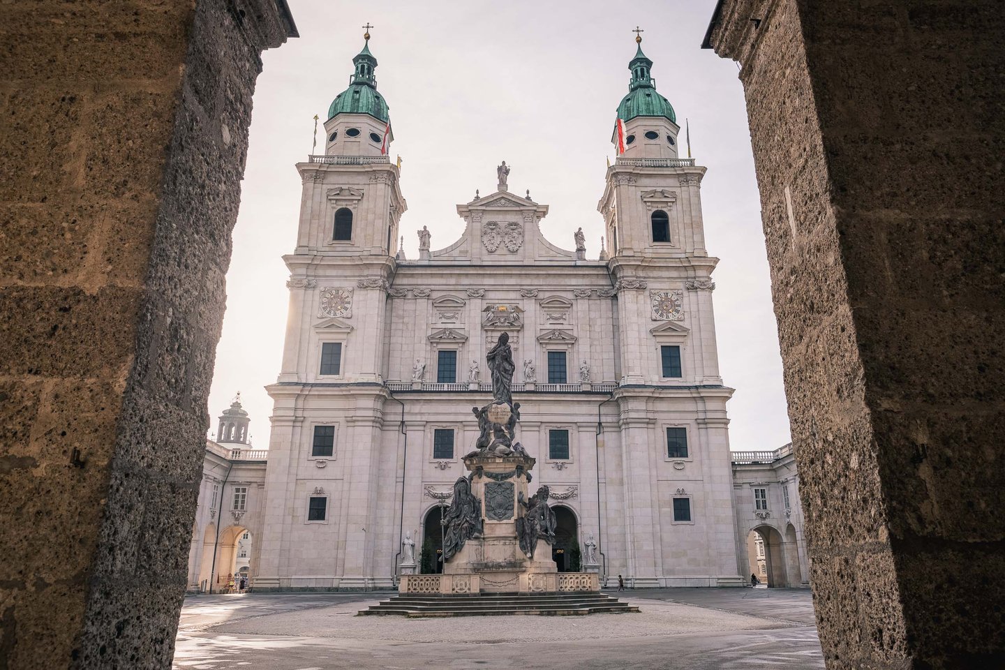 Salzburg Cathedral baroque facade with Marian column framed by Residenzplatz archway in Salzburg