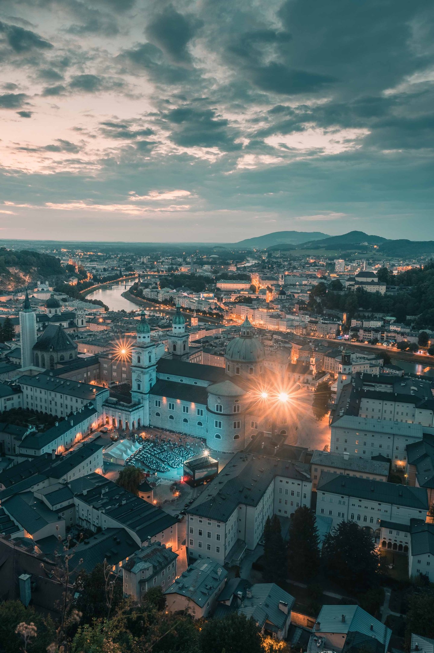 Salzburg old town glows at dusk with cathedral lights and festival seating seen from the fortress.