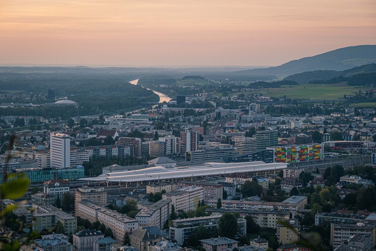 Salzburg Hauptbahnhof and northern city with Salzach bend visible at dusk from Kapuzinerberg