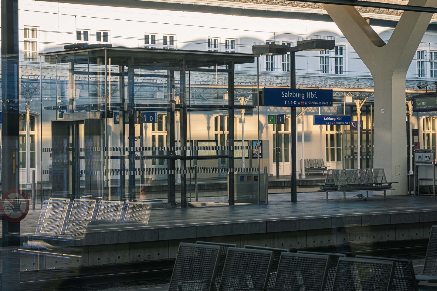 Empty platform benches and glass waiting shelter at Salzburg Hauptbahnhof in Salzburg