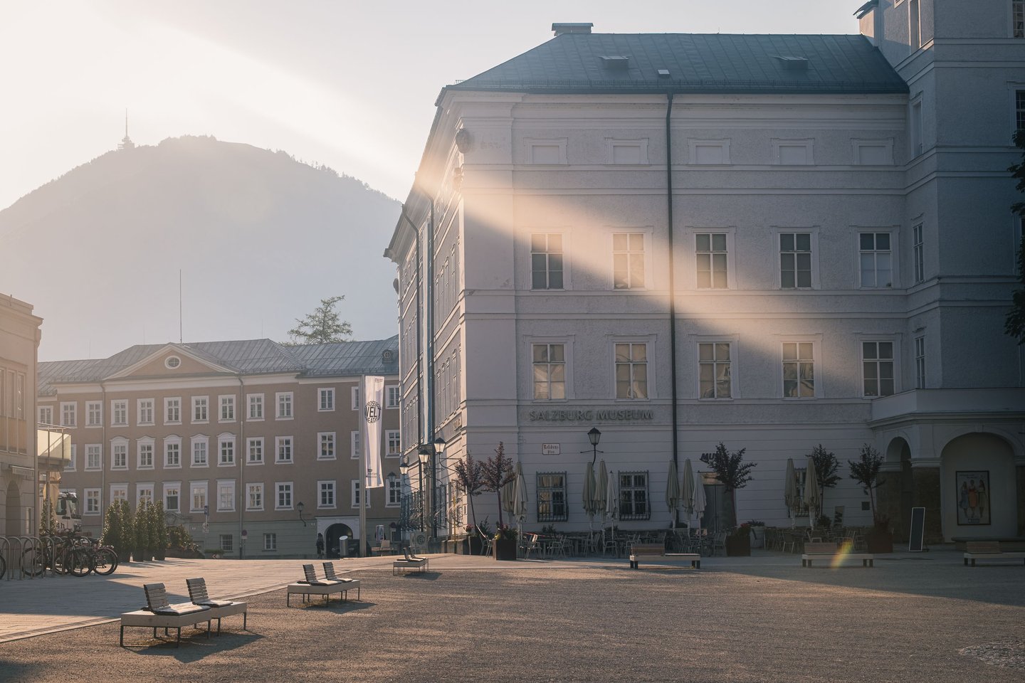 Salzburg Museum and Mozartplatz at sunrise with Gaisberg mountain rising in the hazy distance.