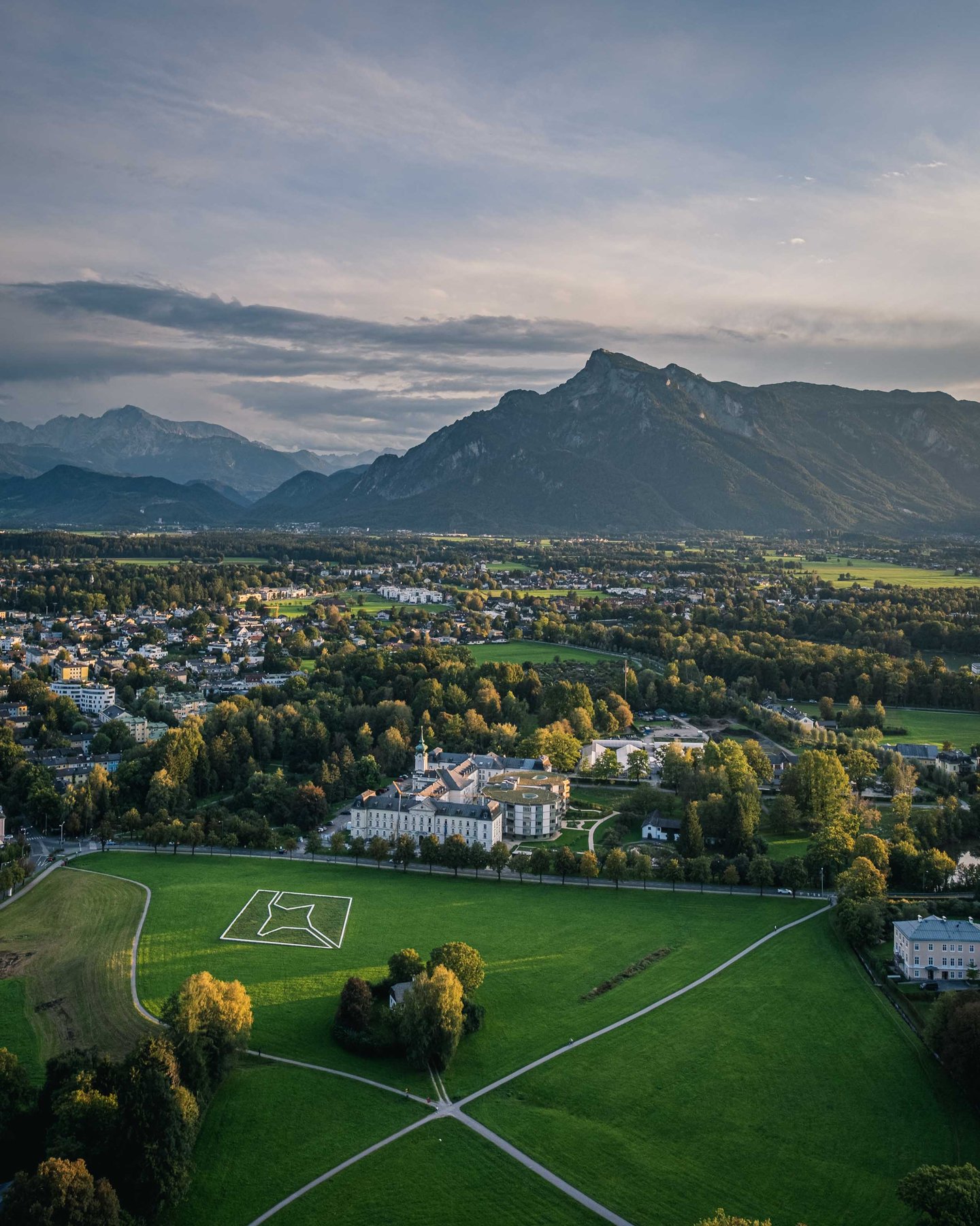 Aerial view of palace and open fields in the Salzburg-Nonntal area below the Untersberg massif near Salzburg