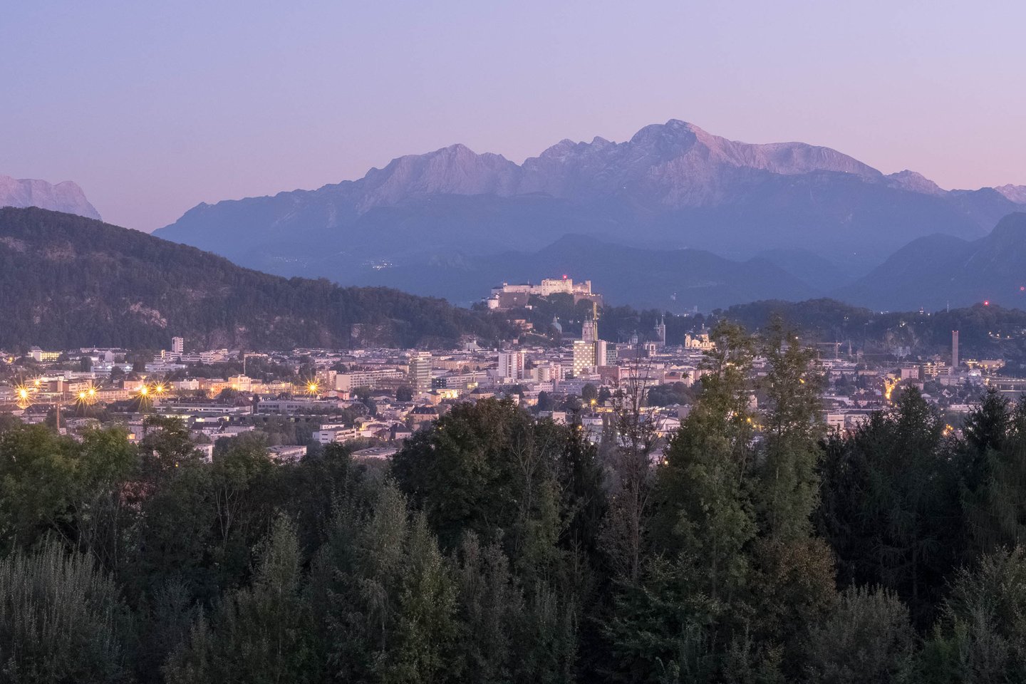 Salzburg cityscape with fortress and Untersberg mountain under pink alpenglow at dusk