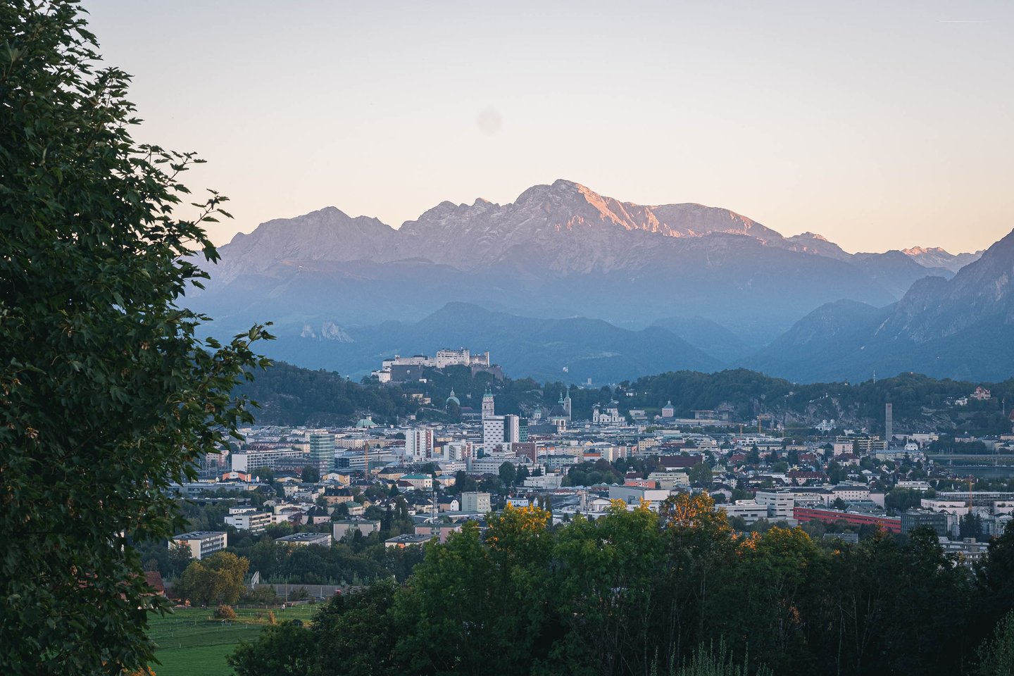 Salzburg cityscape with Hohensalzburg fortress and Untersberg massif beyond at sunset