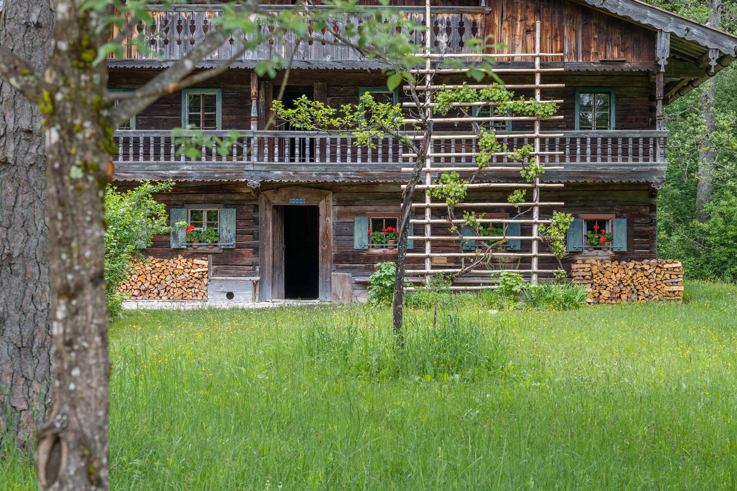 Historic wooden farmhouse with stacked firewood and carved balconies at Salzburger Freilichtmuseum in Grossgmain