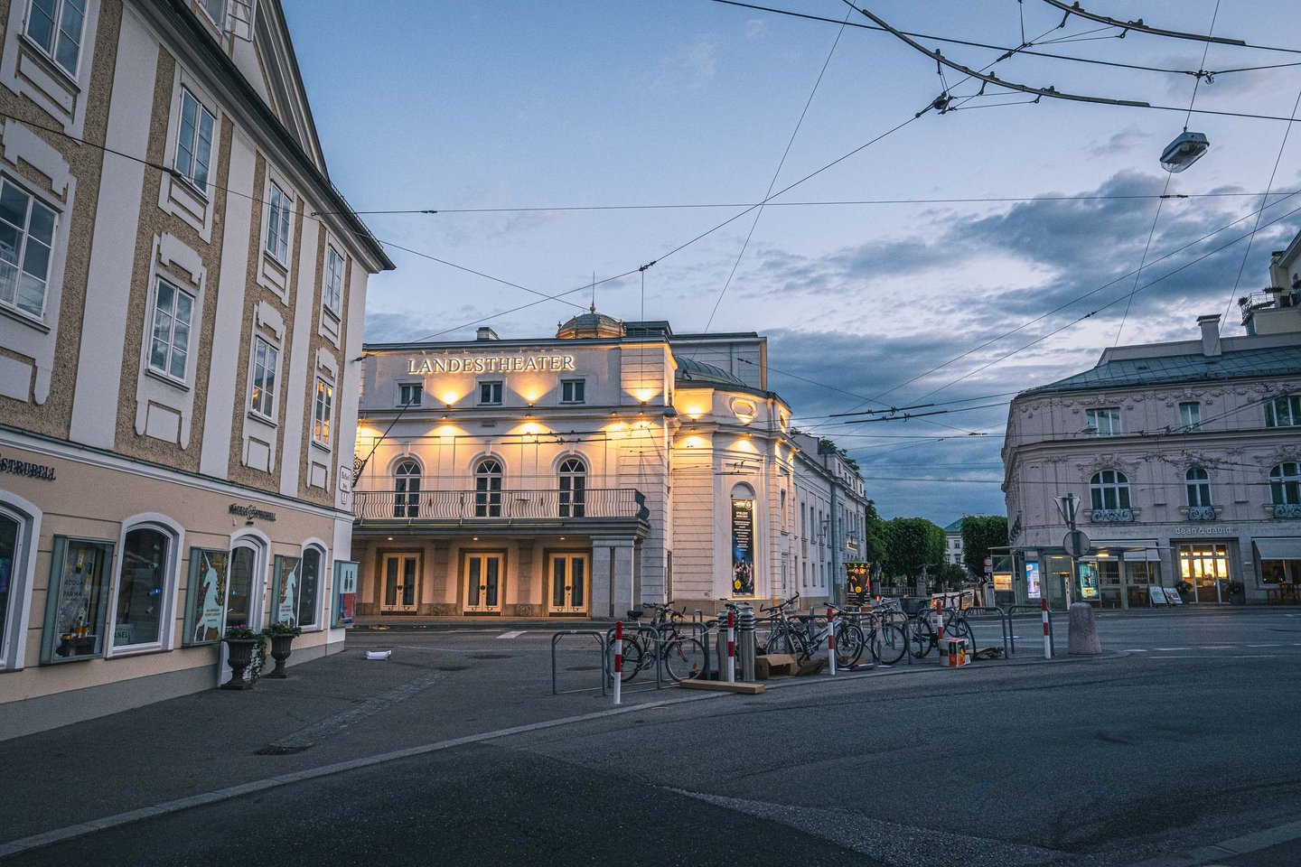 Salzburger Landestheater facade illuminated before dawn with empty streets in Salzburg Neustadt.