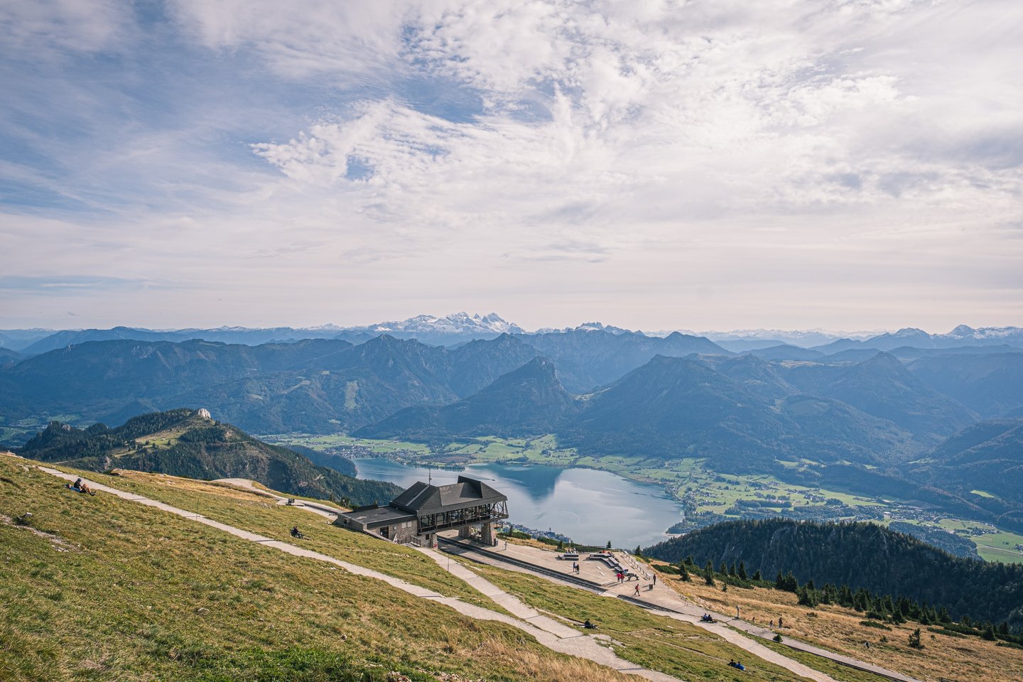From the grassy Schafberg summit plateau the eye runs past the small railway station down to the Wolfgangsee and on to range after range ending in the snowy Dachstein.