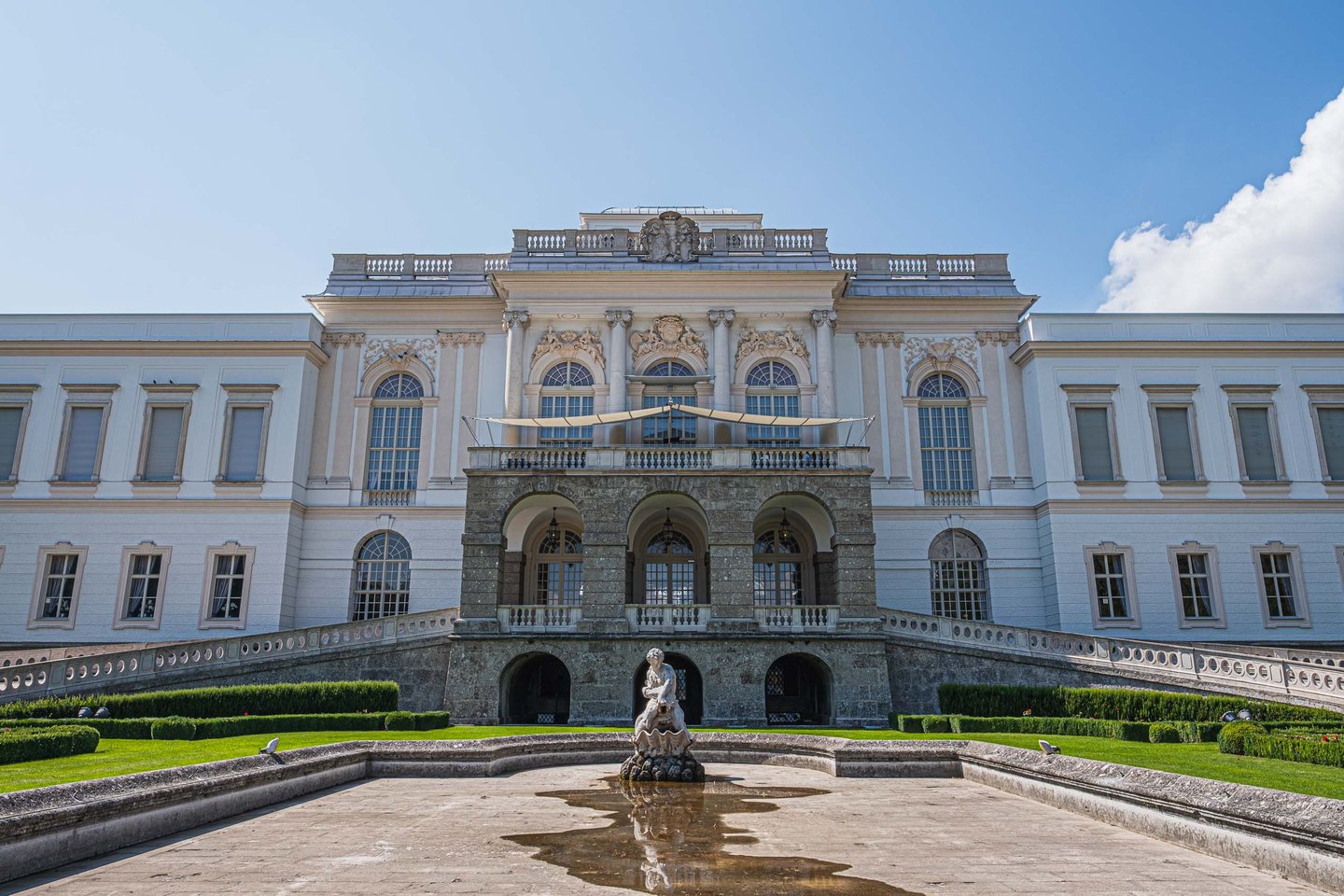 Baroque facade of Schloss Klessheim casino with garden and fountain in Salzburg.