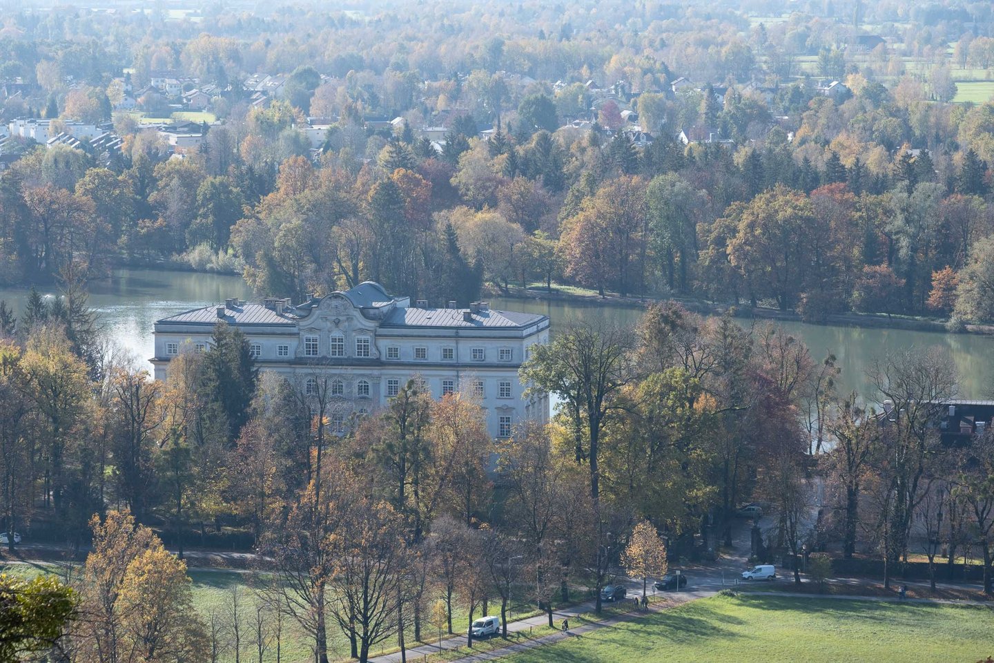 Schloss Leopoldskron rises beside its reflecting pond amid autumn trees in Salzburg.