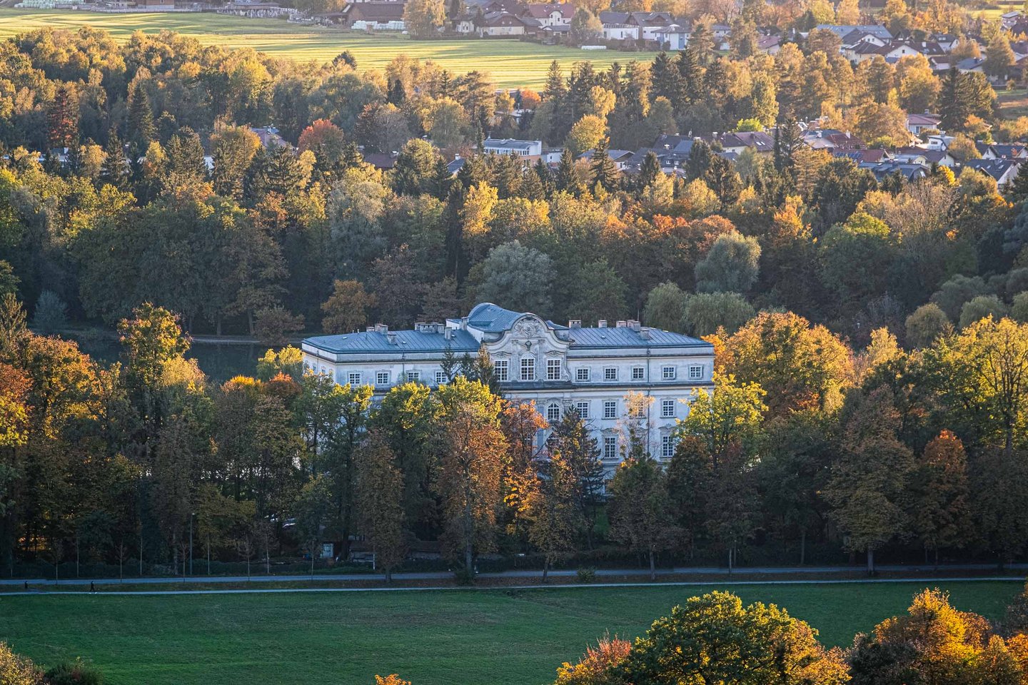Schloss Leopoldskron palace nestled among autumn foliage seen from the Monchsberg in Salzburg.