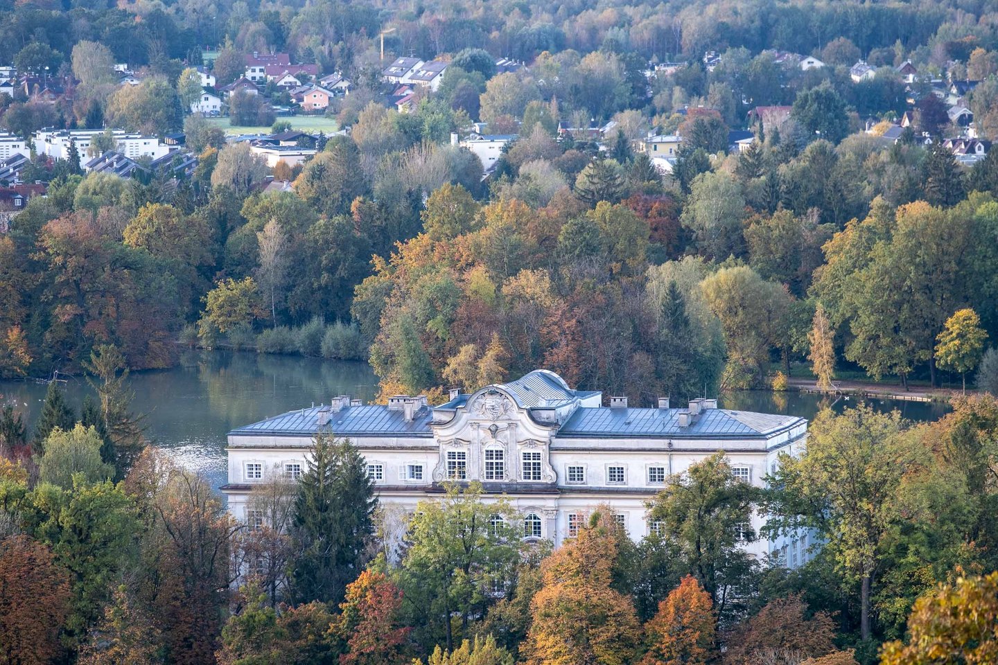 Schloss Leopoldskron palace reflected in its pond amid autumn trees in Salzburg.