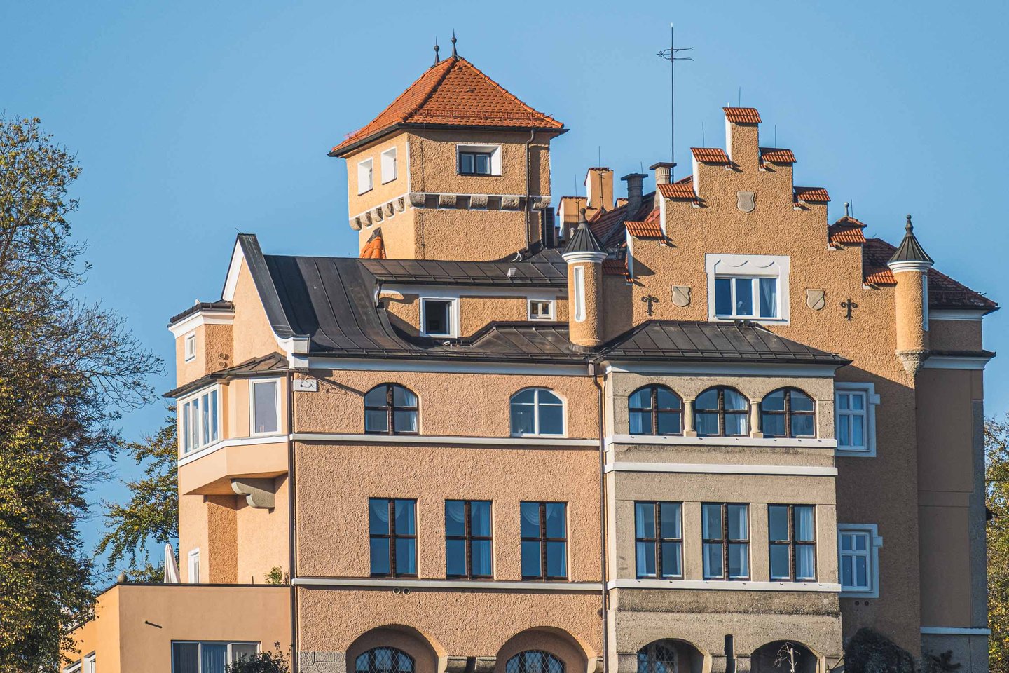 Schloss Moenchstein hotel facade with turret and embedded coat of arms under blue sky on Moenchsberg in Salzburg