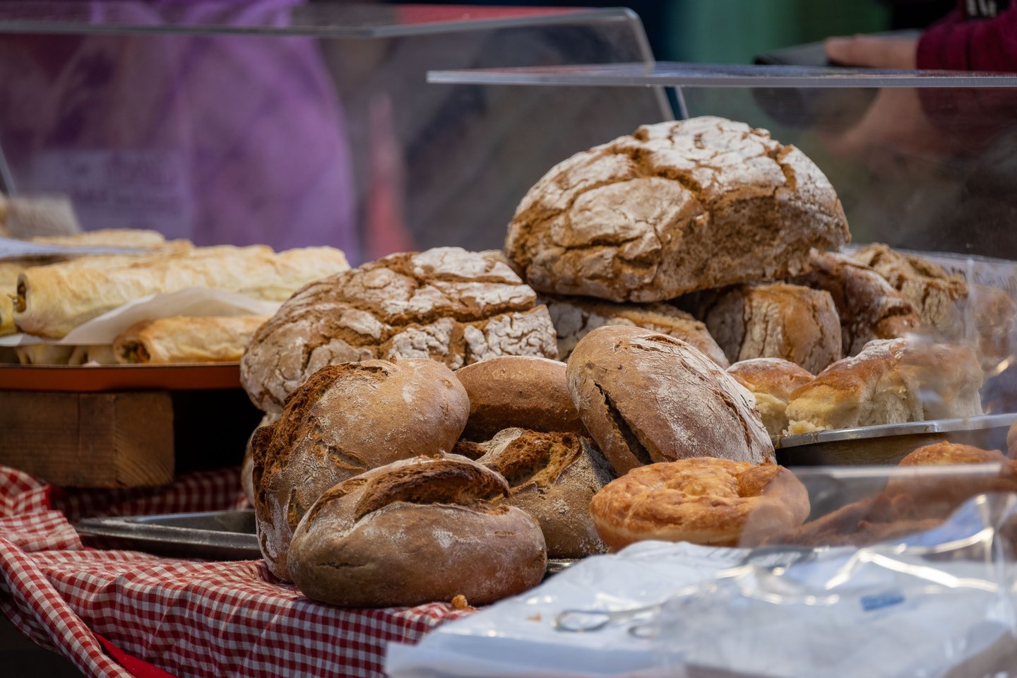 Rustic sourdough loaves stacked on a red gingham cloth at the Schrannenmarkt farmers market in Salzburg