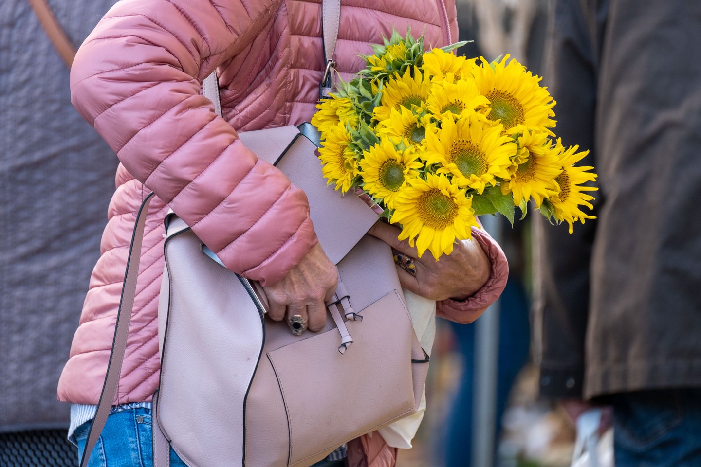 Shopper carries a bouquet of sunflowers in a leather handbag at the Schrannenmarkt in Salzburg