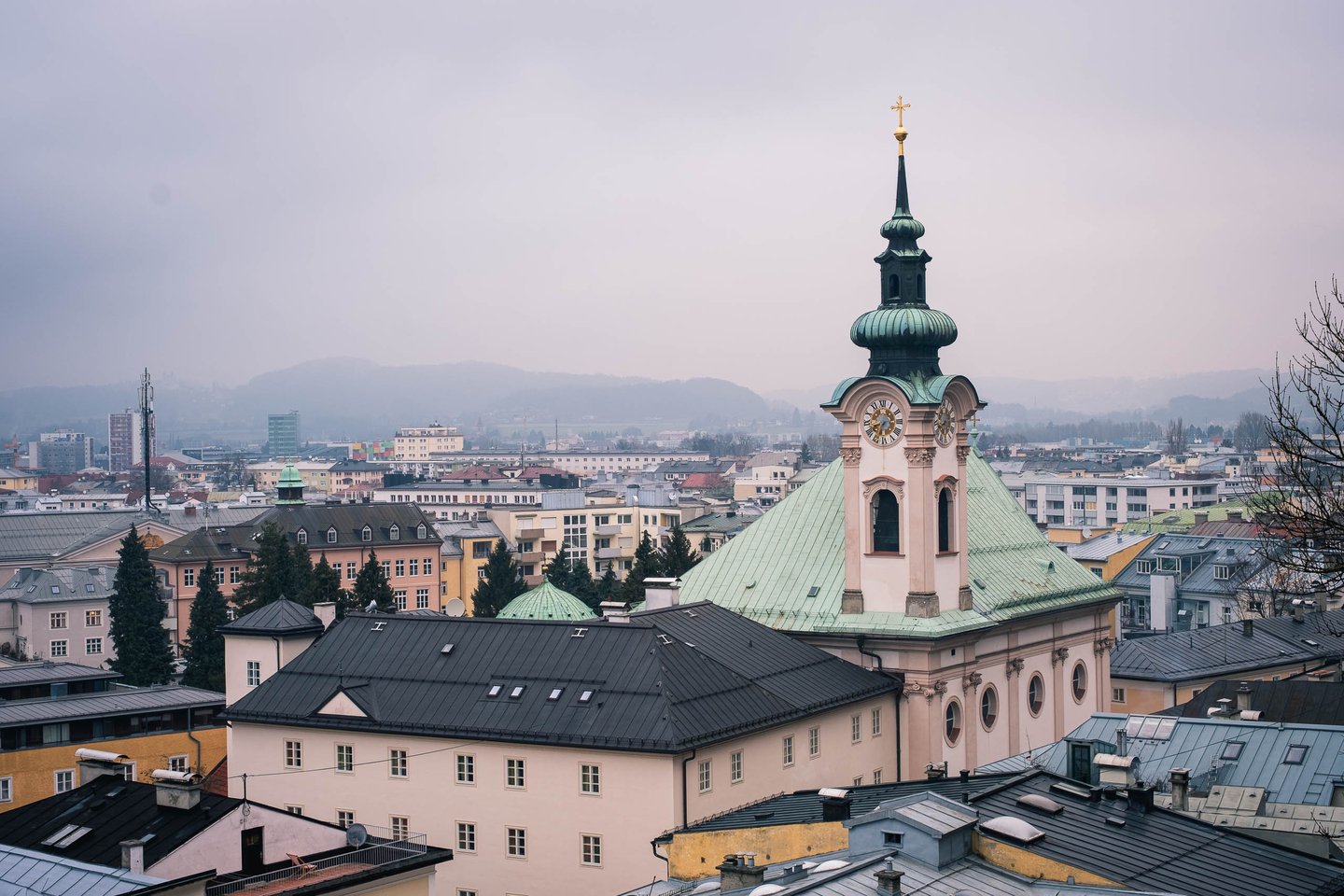 Green onion-domed tower of Sebastianskirche rises over Neustadt rooftops in Salzburg