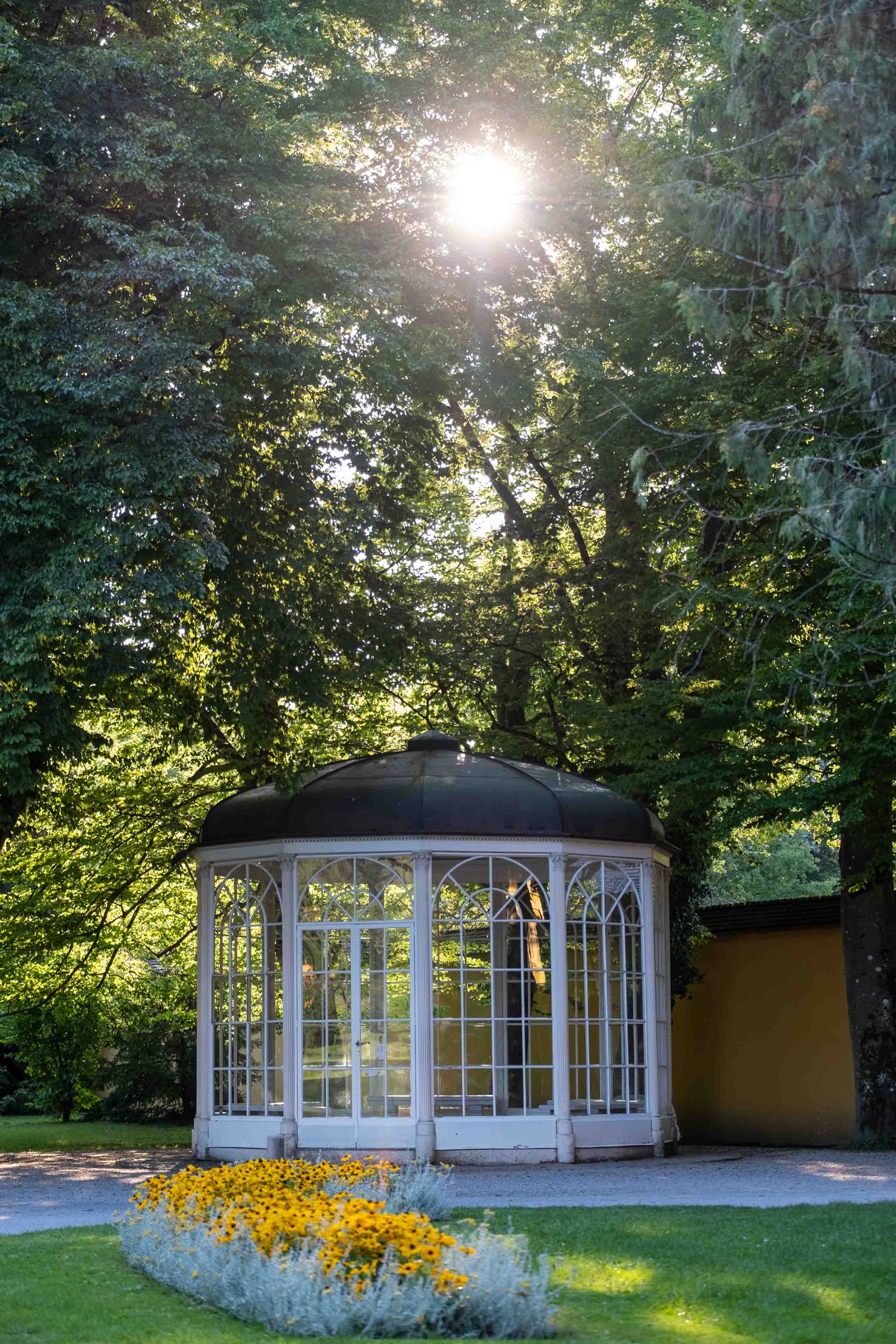 Sound of Music pavilion framed by yellow flowerbed and trees at Hellbrunn in Salzburg.