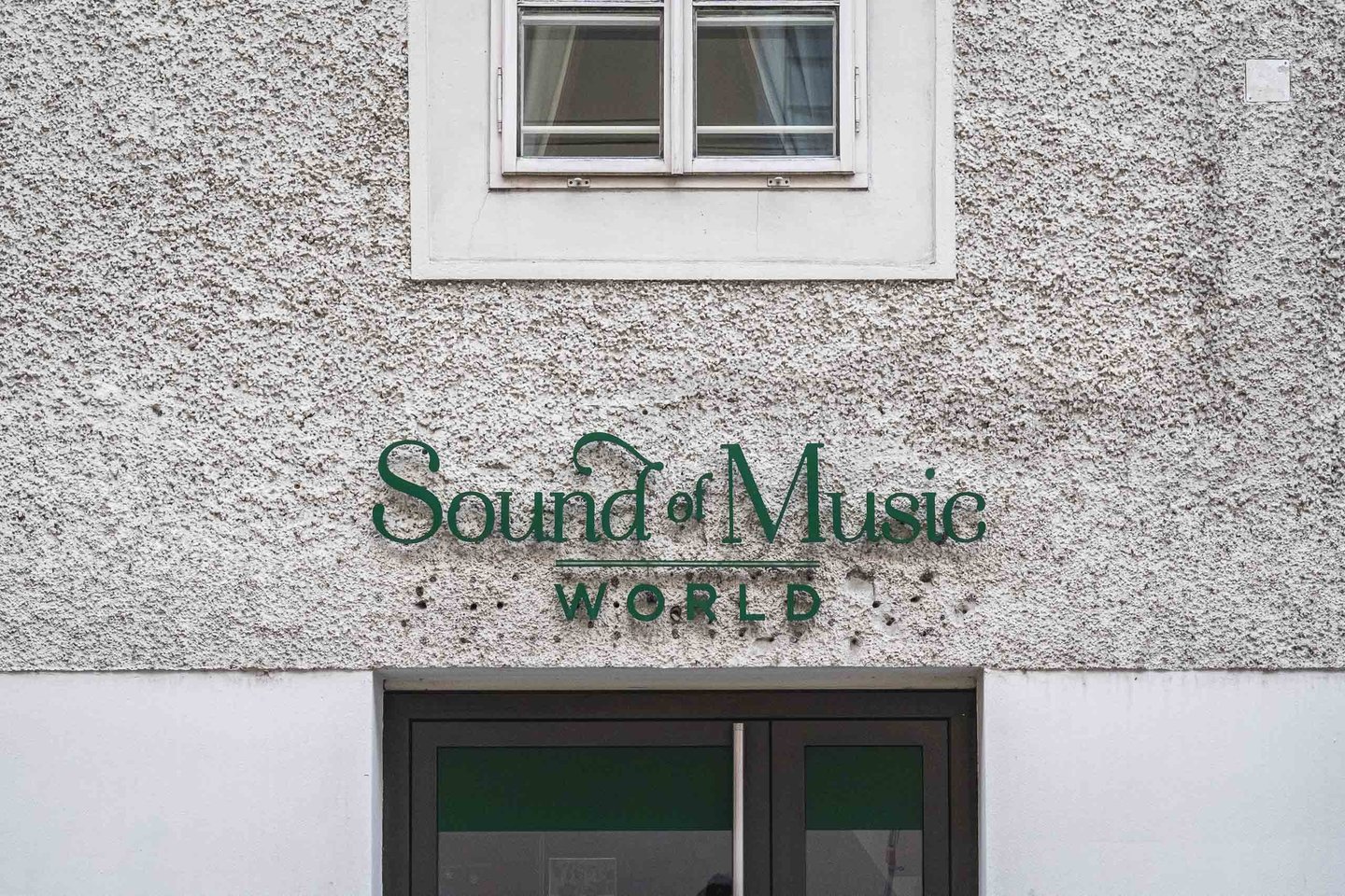 Sound of Music World green lettering signage above entrance door on building facade in Salzburg