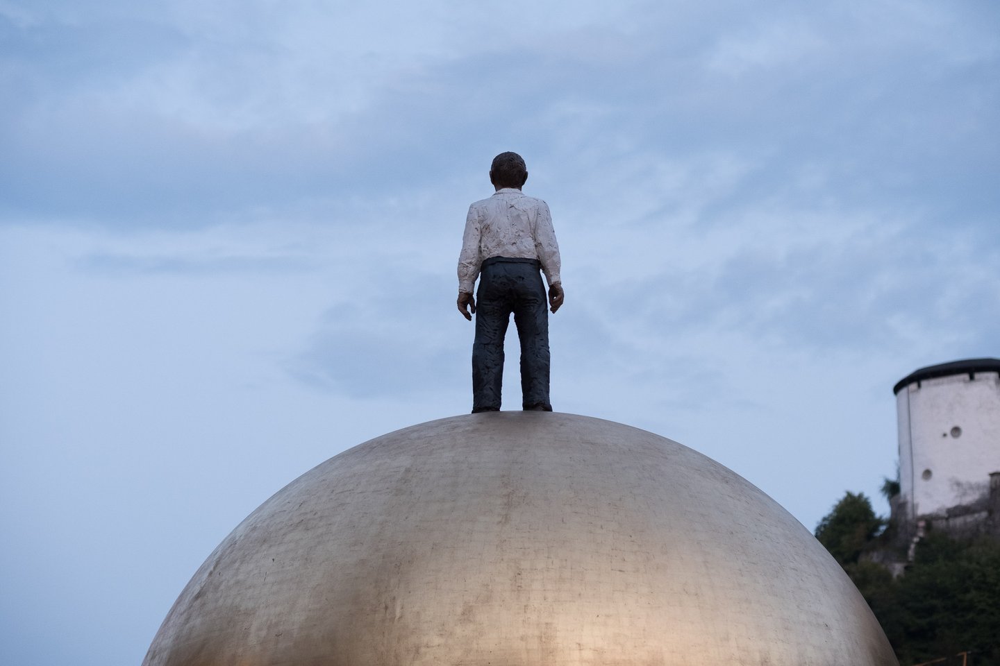 Close view of Sphaera sculpture figure on golden ball against blue sky in Salzburg old town