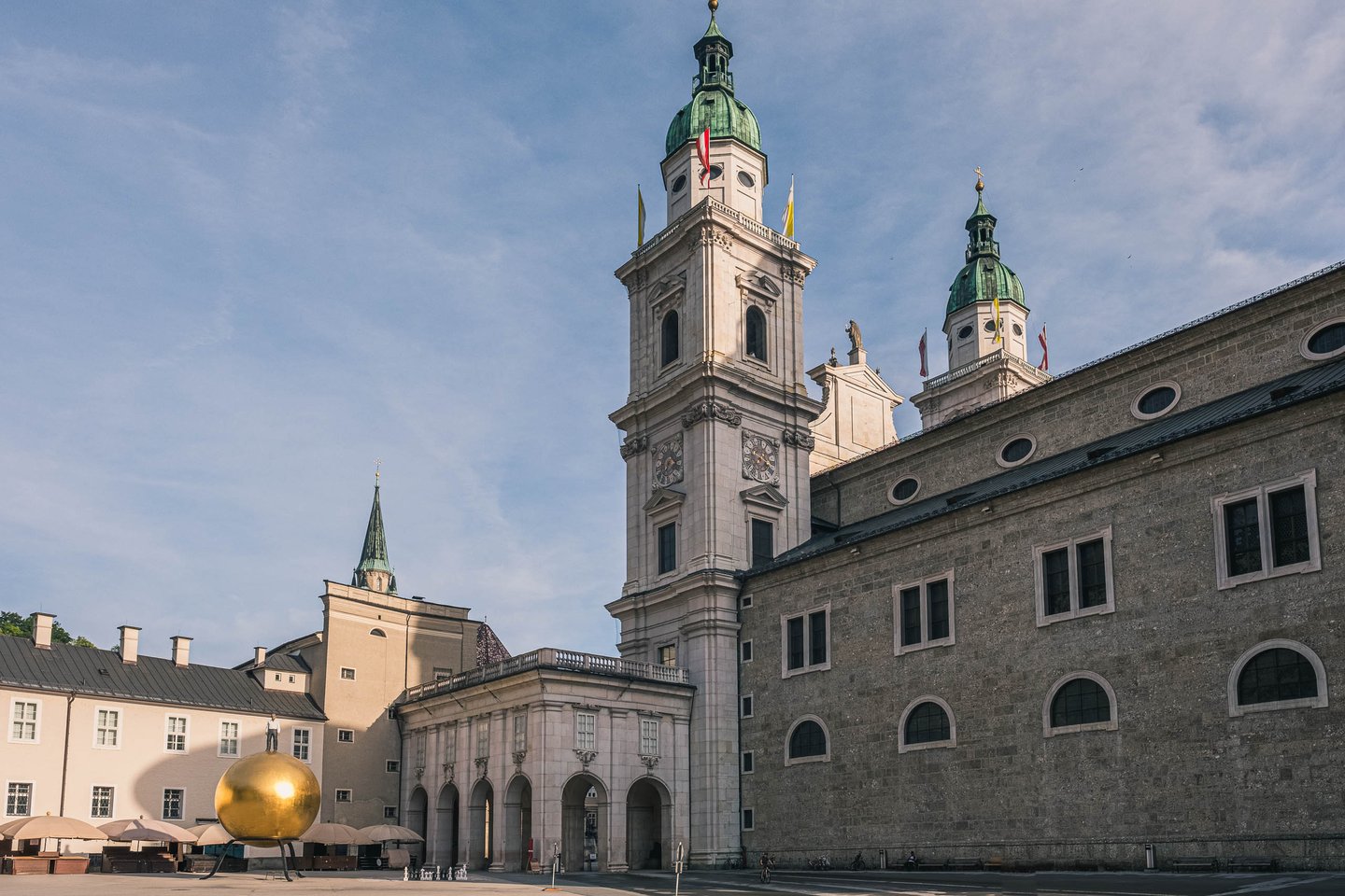 Sphaera golden ball sculpture in front of Salzburg Cathedral towers on Kapitelplatz in Salzburg