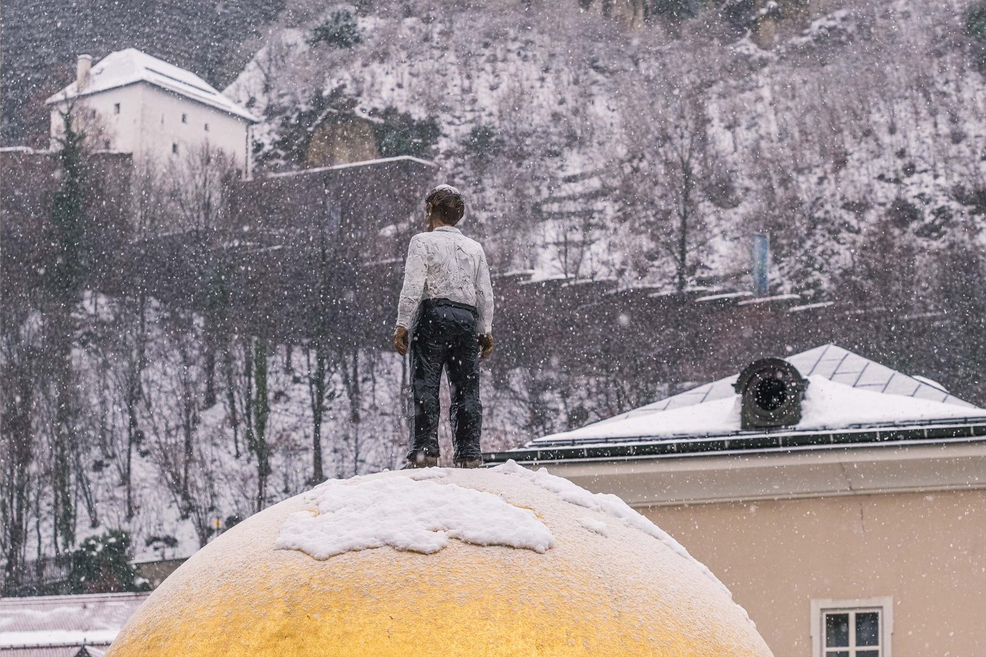 Stephan Balkenhol Sphaera golden sphere sculpture with figure on top covered in snow on Kapitelplatz Salzburg