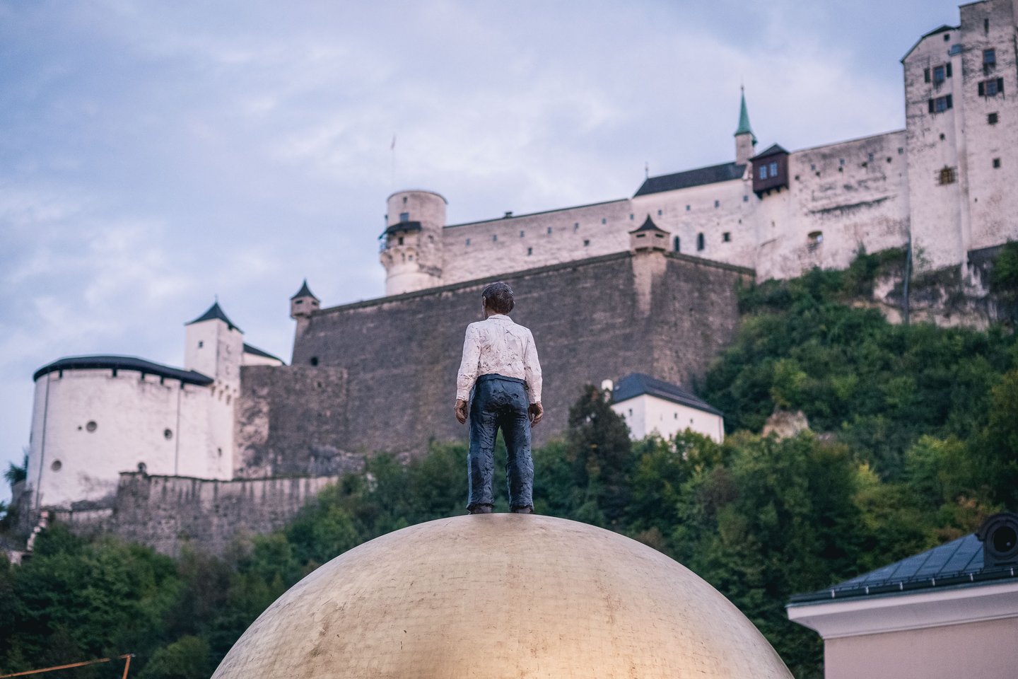 Sphaera golden ball sculpture with figure atop below Hohensalzburg fortress in Salzburg