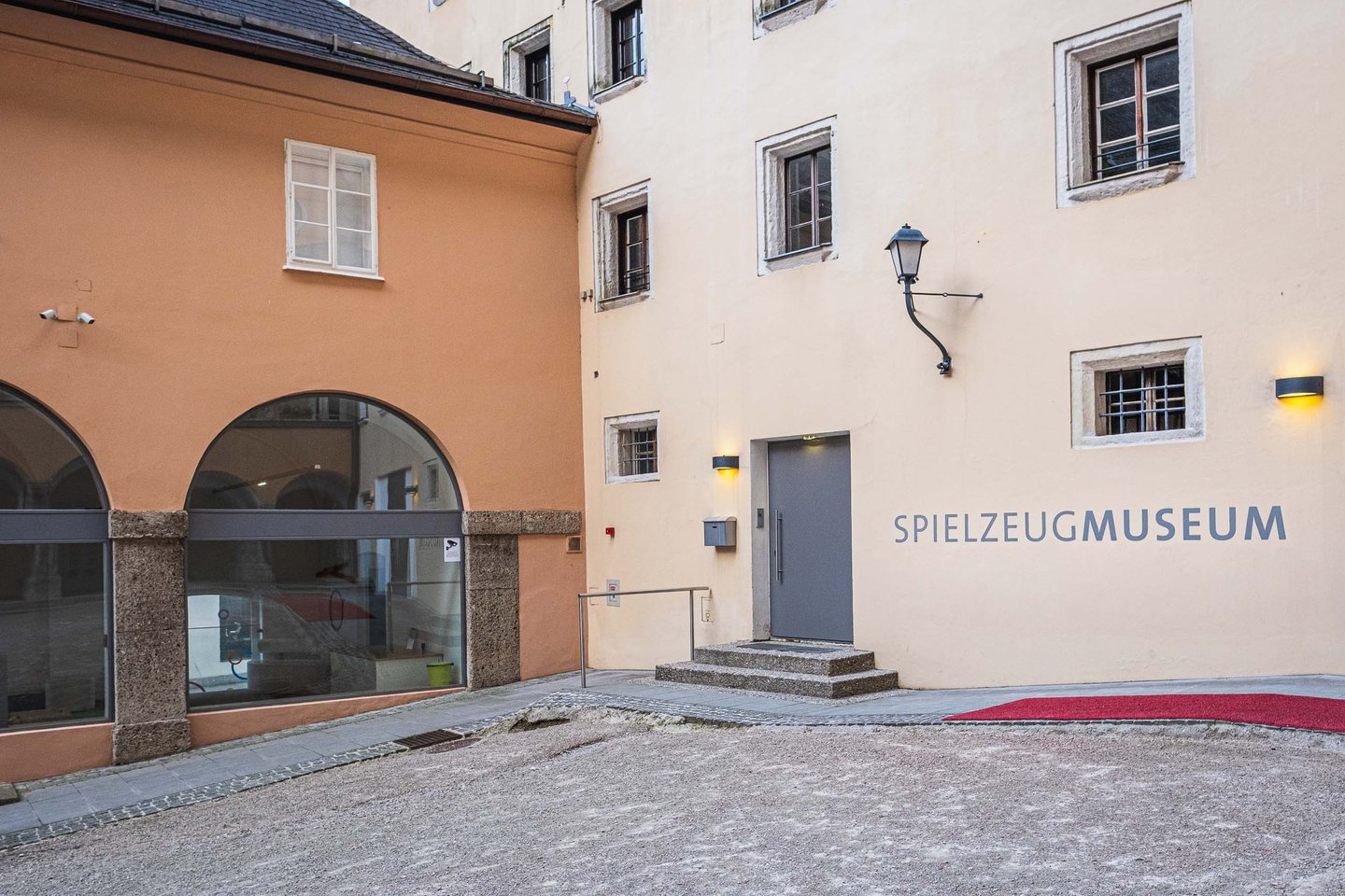 Spielzeugmuseum entrance with red carpet and signage in historic courtyard in Salzburg