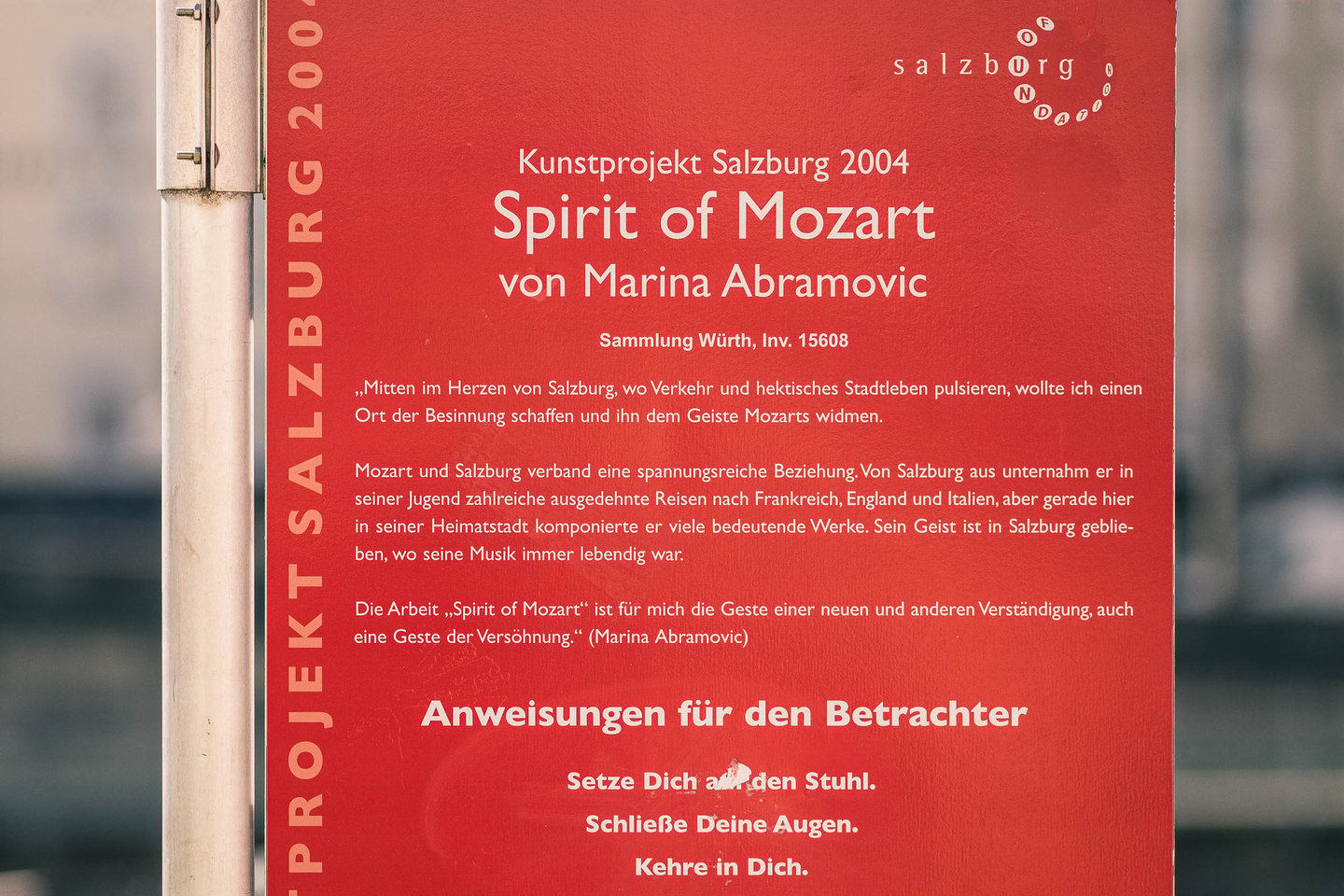 Red information plaque describes the Spirit of Mozart art installation by Marina Abramovic in Salzburg.
