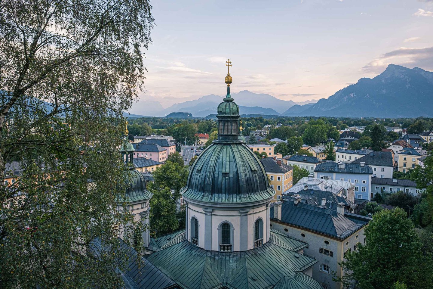 Erhardkirche onion dome rises above Nonntal with the Tennen and Untersberg mountains behind in Salzburg.