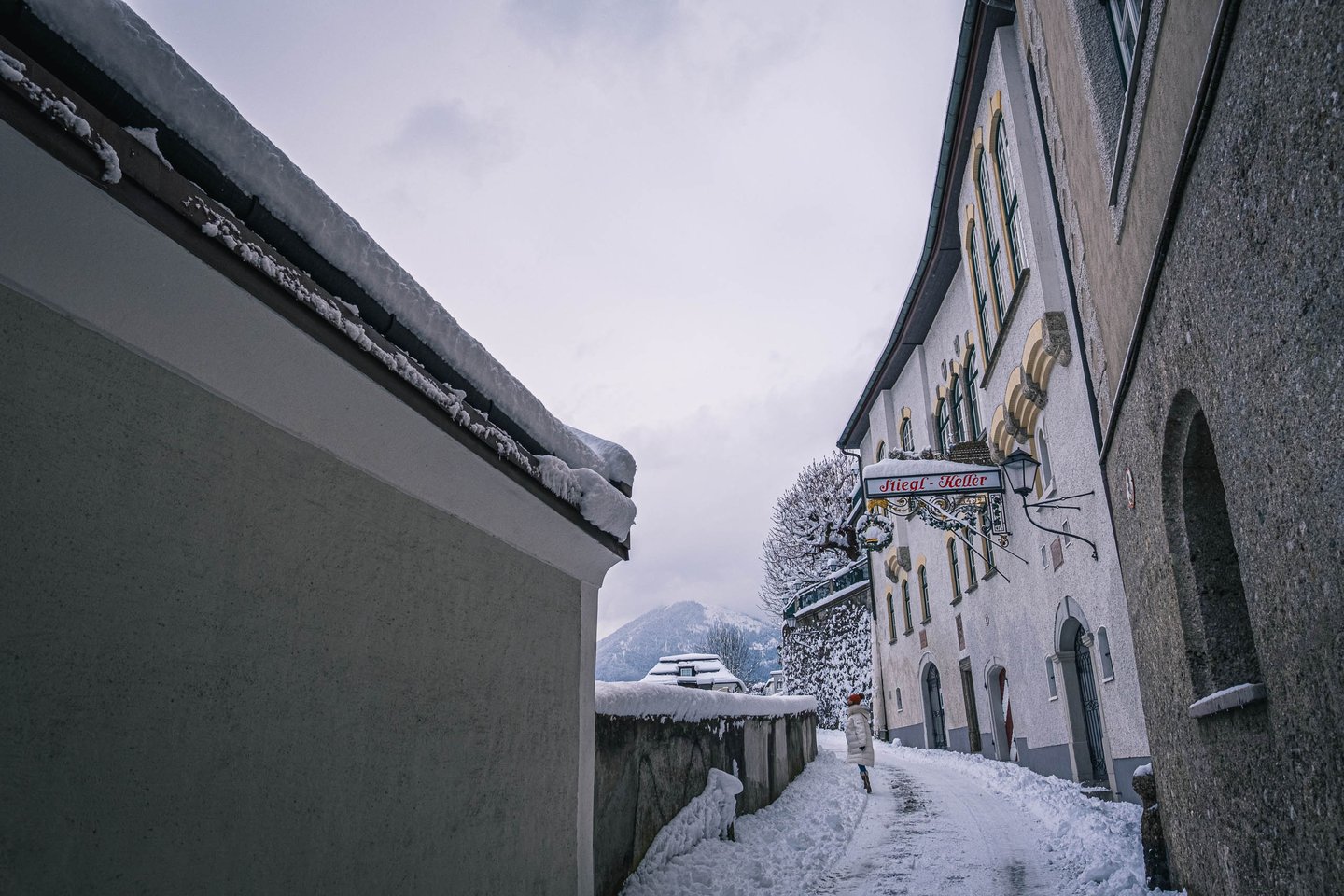 Snowy path on Festungsgasse leads toward the Stieglkeller entrance in Salzburg old town.